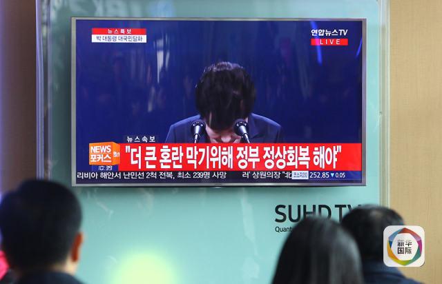 11月4日,在韩国首尔火车站,人们观看总统朴槿惠对国民讲话的电视直播。 (新华社记者姚琪琳摄)